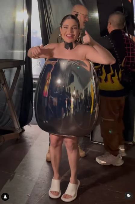 Mulher sorrindo com um vestido-ovo espelhado e sandália branca